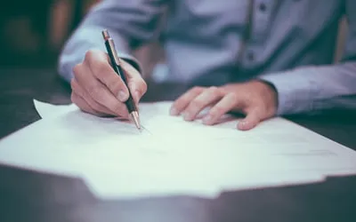 Hands signing a letter at a desk